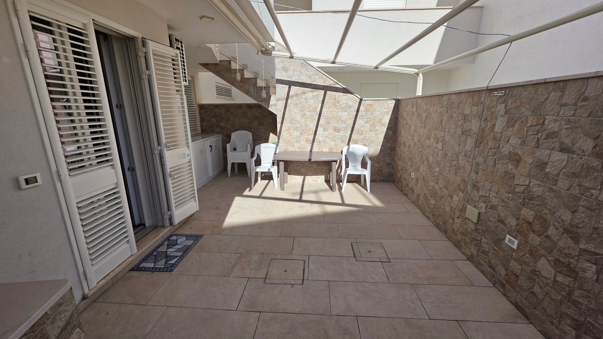Terrazza con tavolo, sedie e doccia esterna